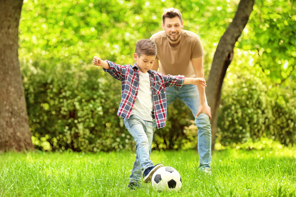Dad,And,Son,Playing,Football,Together,On,Green,Meadow
